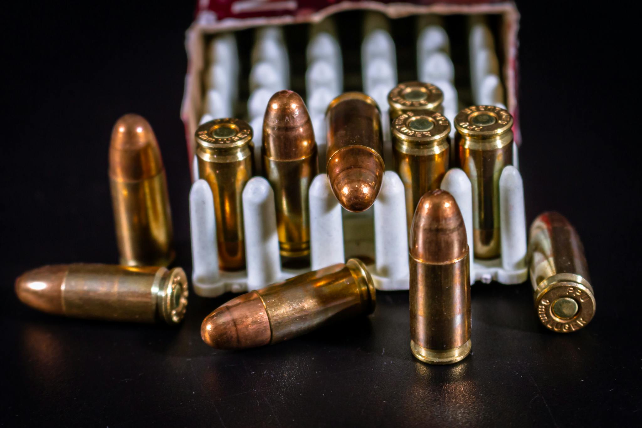 Detailed image of brass bullets and box on a black surface, showcasing ammunition.