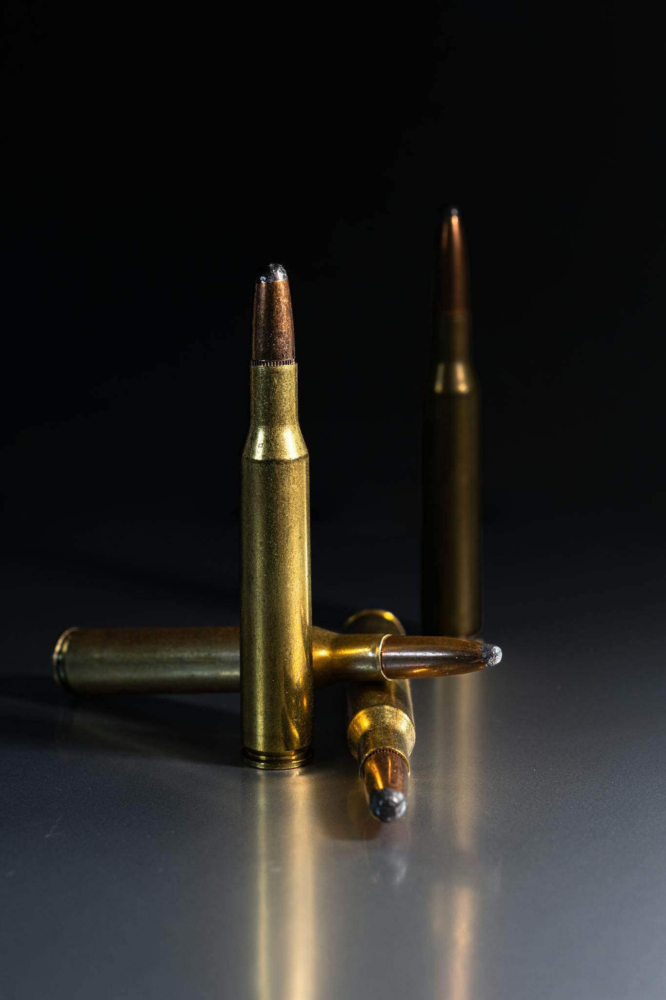 Detailed shot of rifle bullets standing on a reflective surface, showcasing metallic textures.